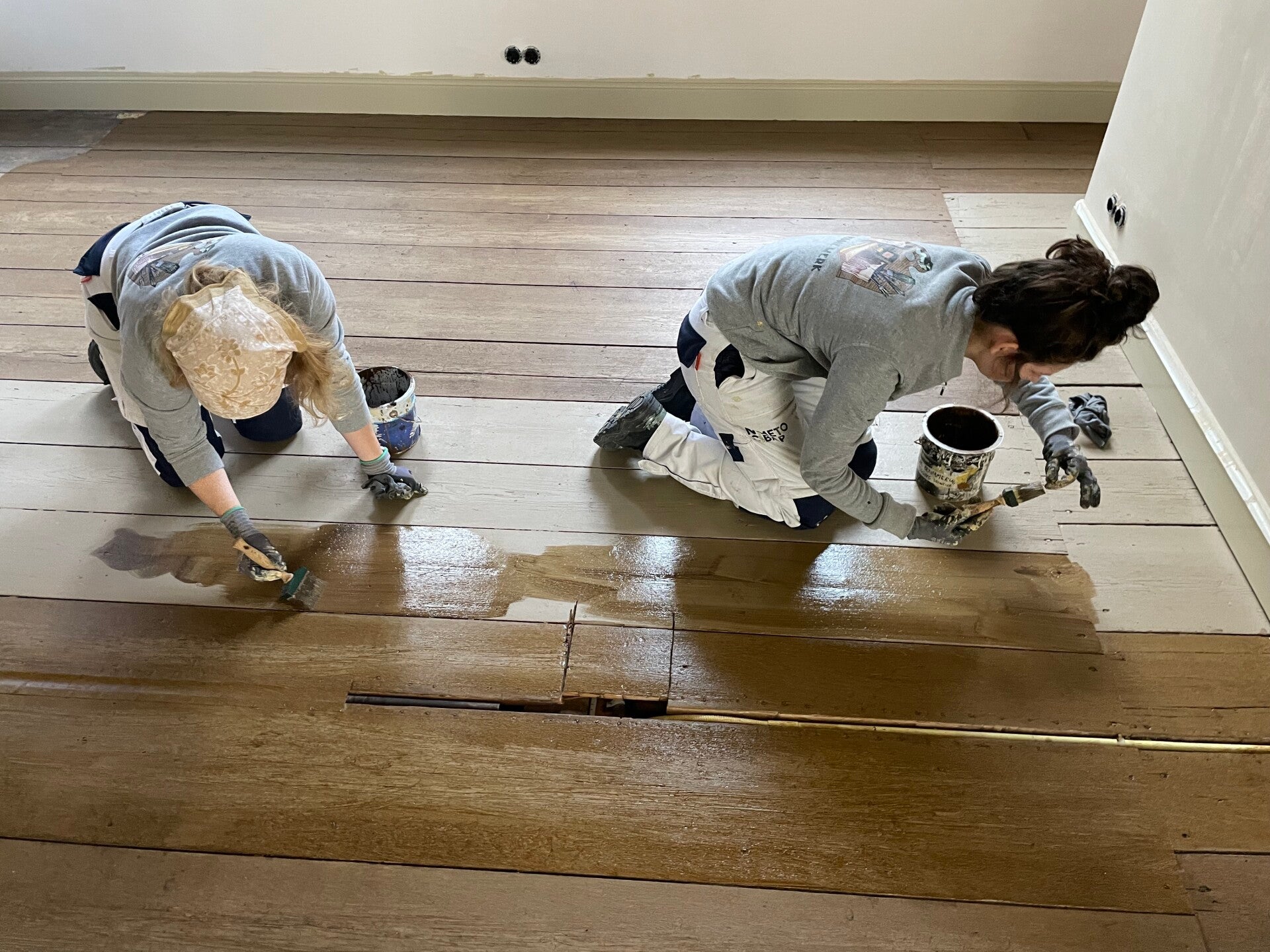 reconstructie van de geschilderde houtimitatie op de houten vloer door stagiars
