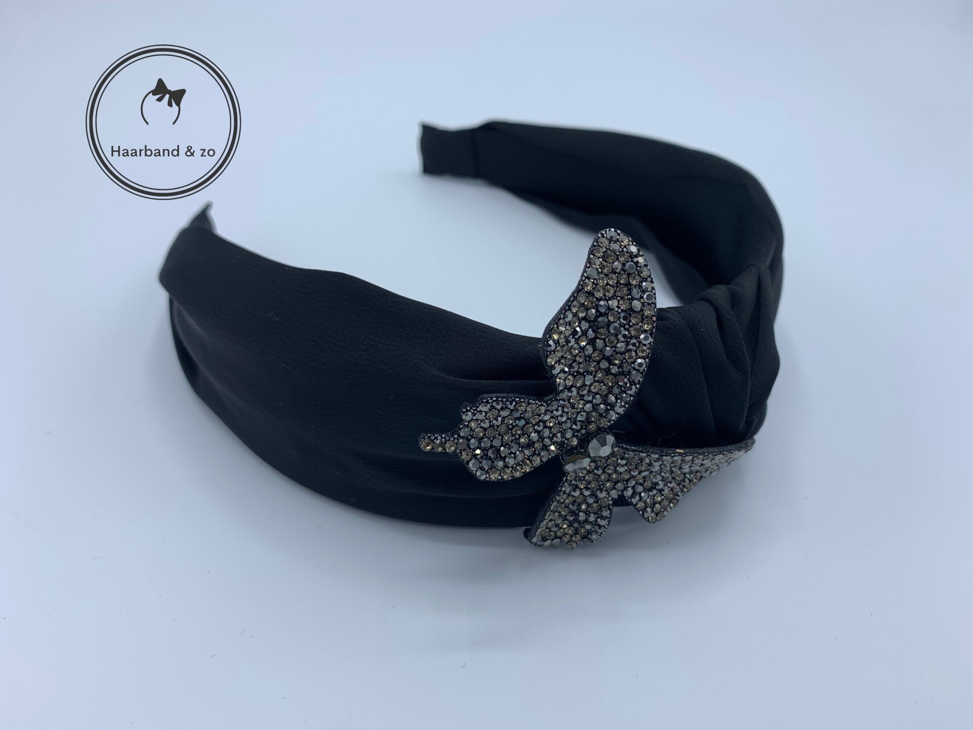 Brede booghaarband van zwart satijn, met glittervlinder (art.nr. 260-01)