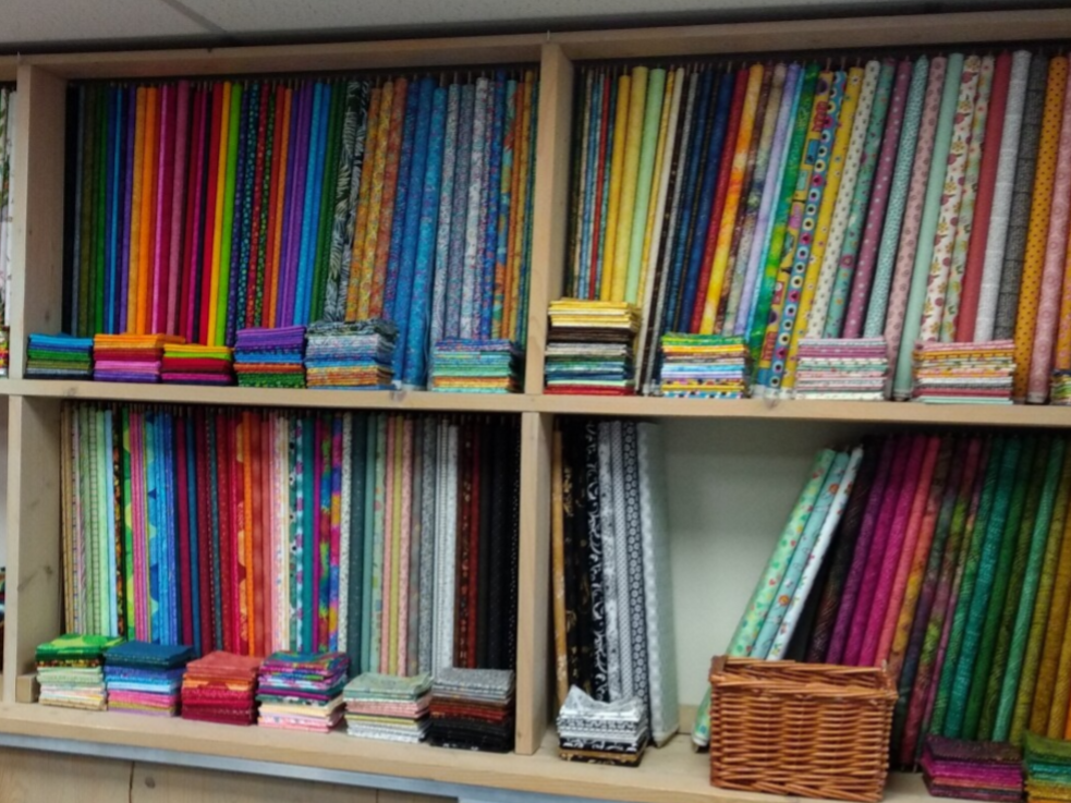 kast in qwille met rollen quiltstoffen naast elkaar. fat quarters ervoor