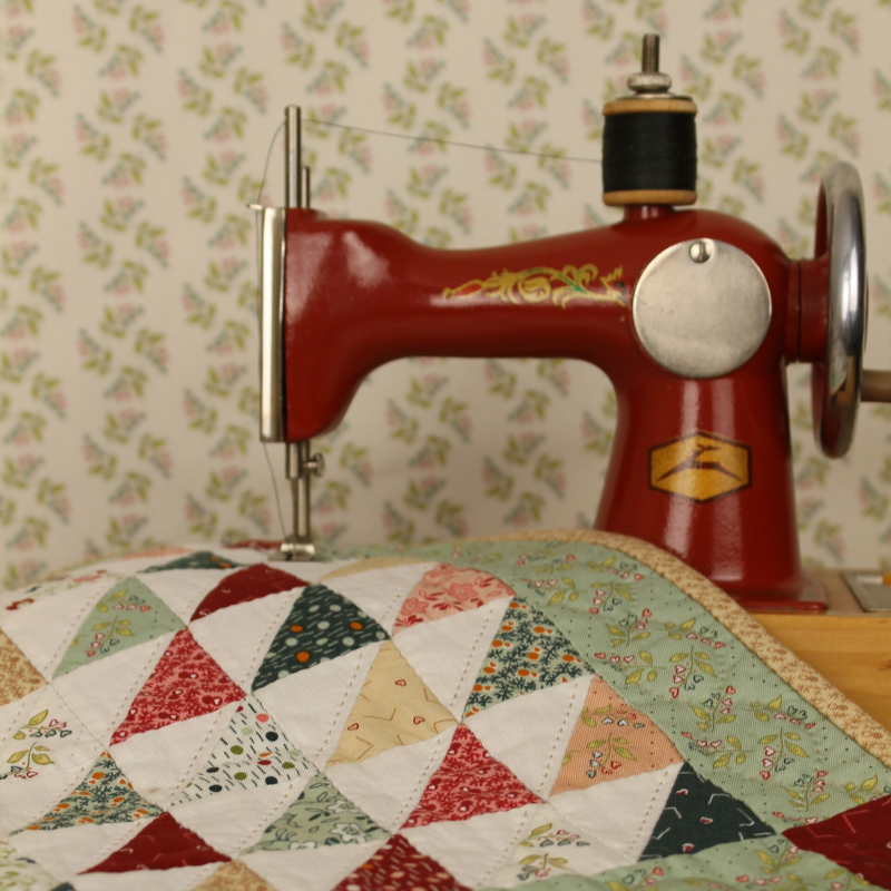 oude naaimachine en driehoeken quilt voor een vintage behang