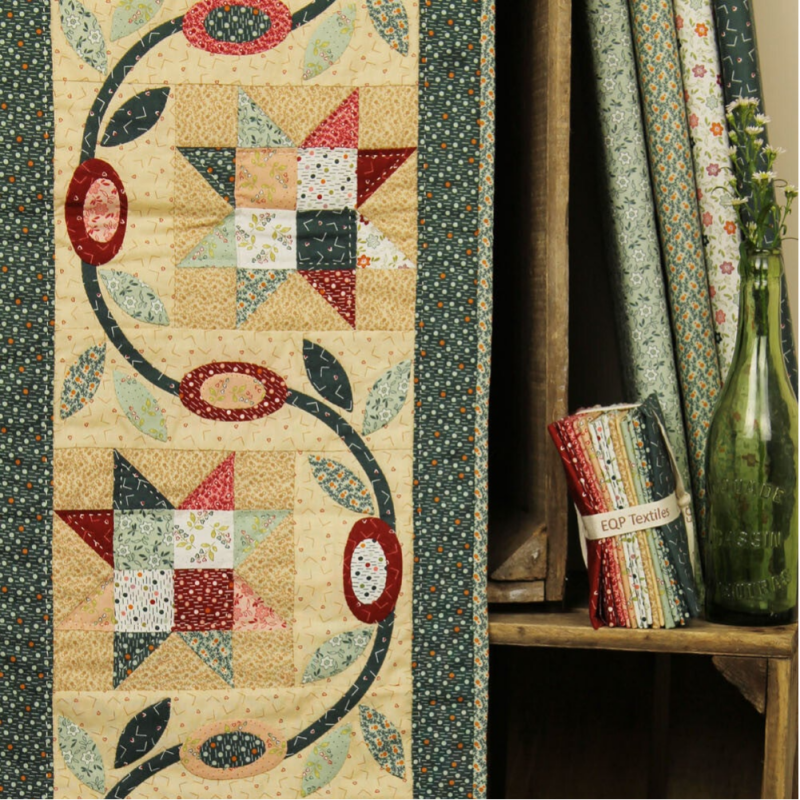 quilt met sterren en bloemen, in kleuren groen, geel en rood.