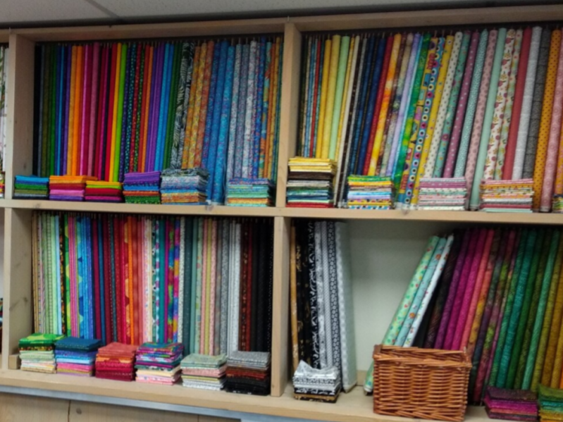 kast in qwille met rollen quiltstoffen naast elkaar. fat quarters ervoor