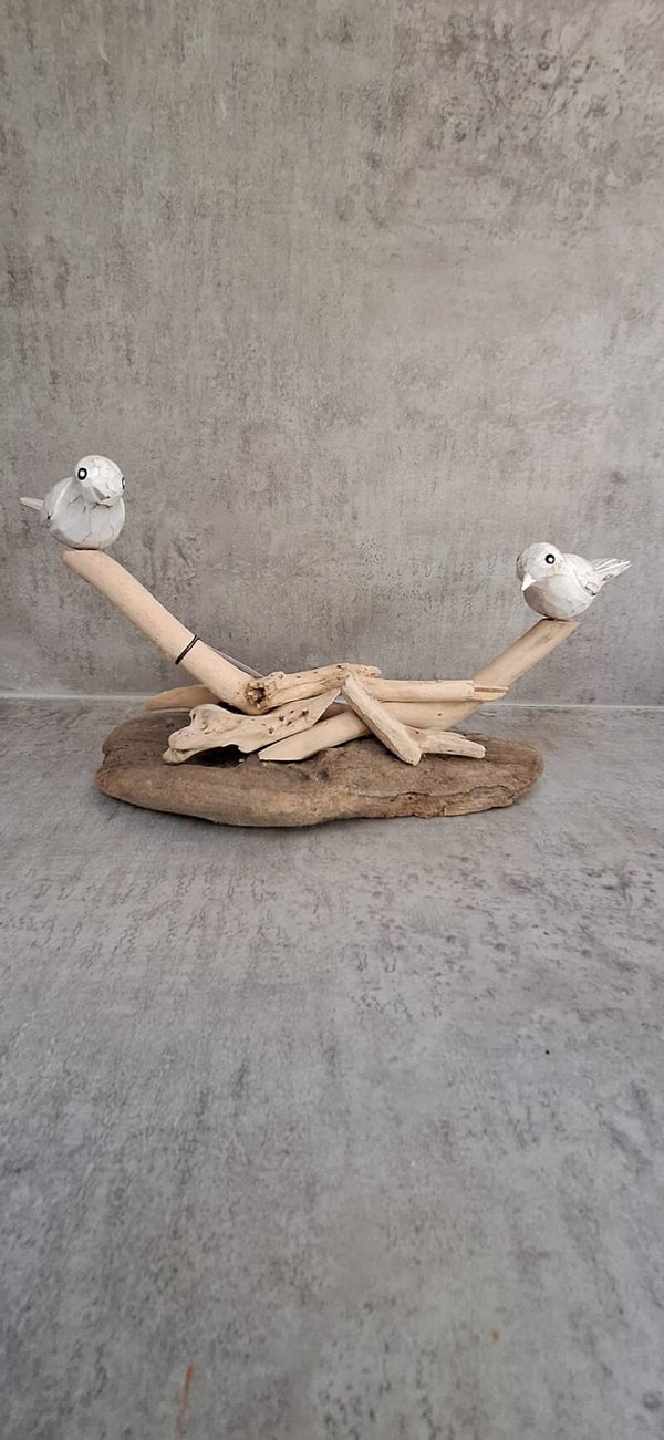 Twee houten vogels op driftwood.
