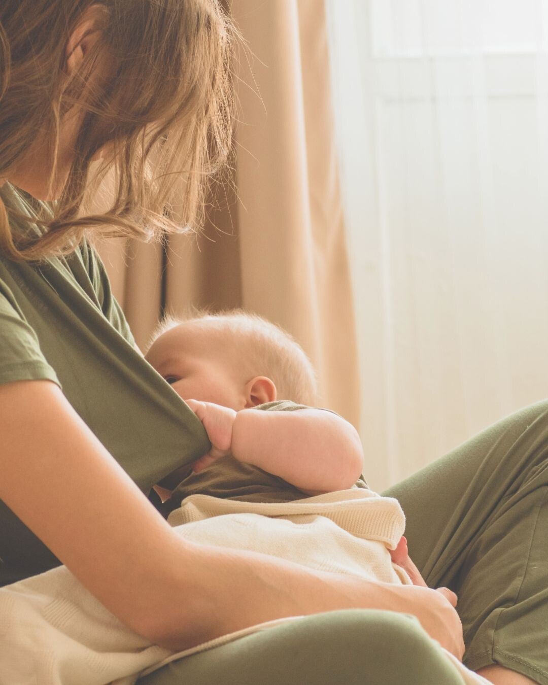 A lady feeding her baby. Holding a cloth to prepare for milk let-down. 
