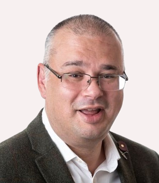 This image shows a smiling white man with short hair, glasses, and a tweed jacket. Carl is committed to financial inclusion and accessibility.