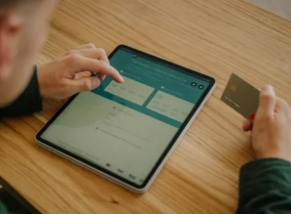 A white man holding his bank card is confused trying to use digital banking on his tablet.