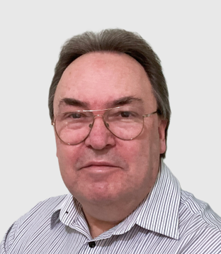 This image shows a smiling white man with glasses, grey hair, and a striped shirt. Trevor is committed to accessibility and social inclusion.