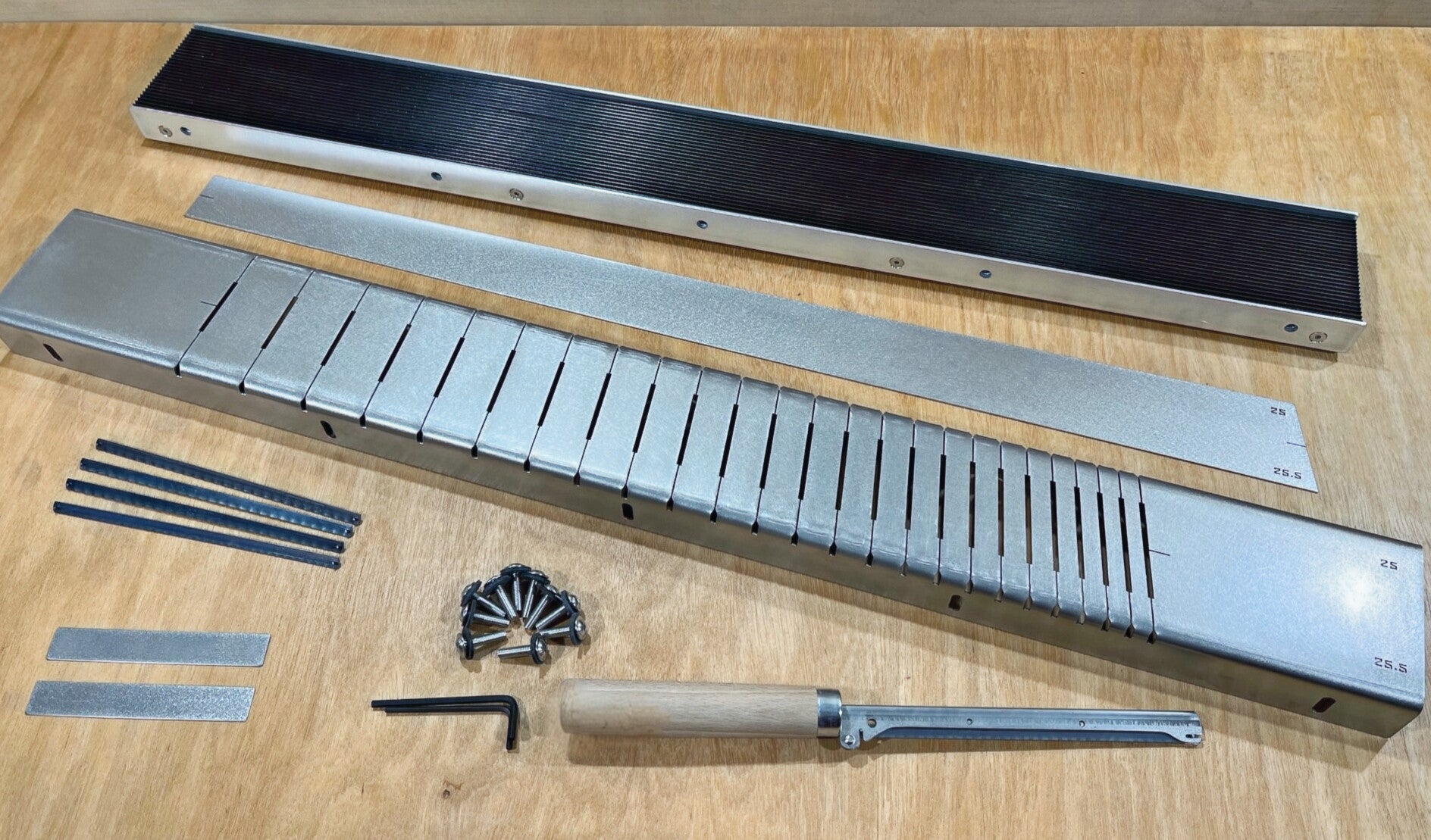 GMC Luthier Tools Multiscale fret slotting jig box laid out on a bench with slotting template, layout gauge, fretsaw and spare blades.