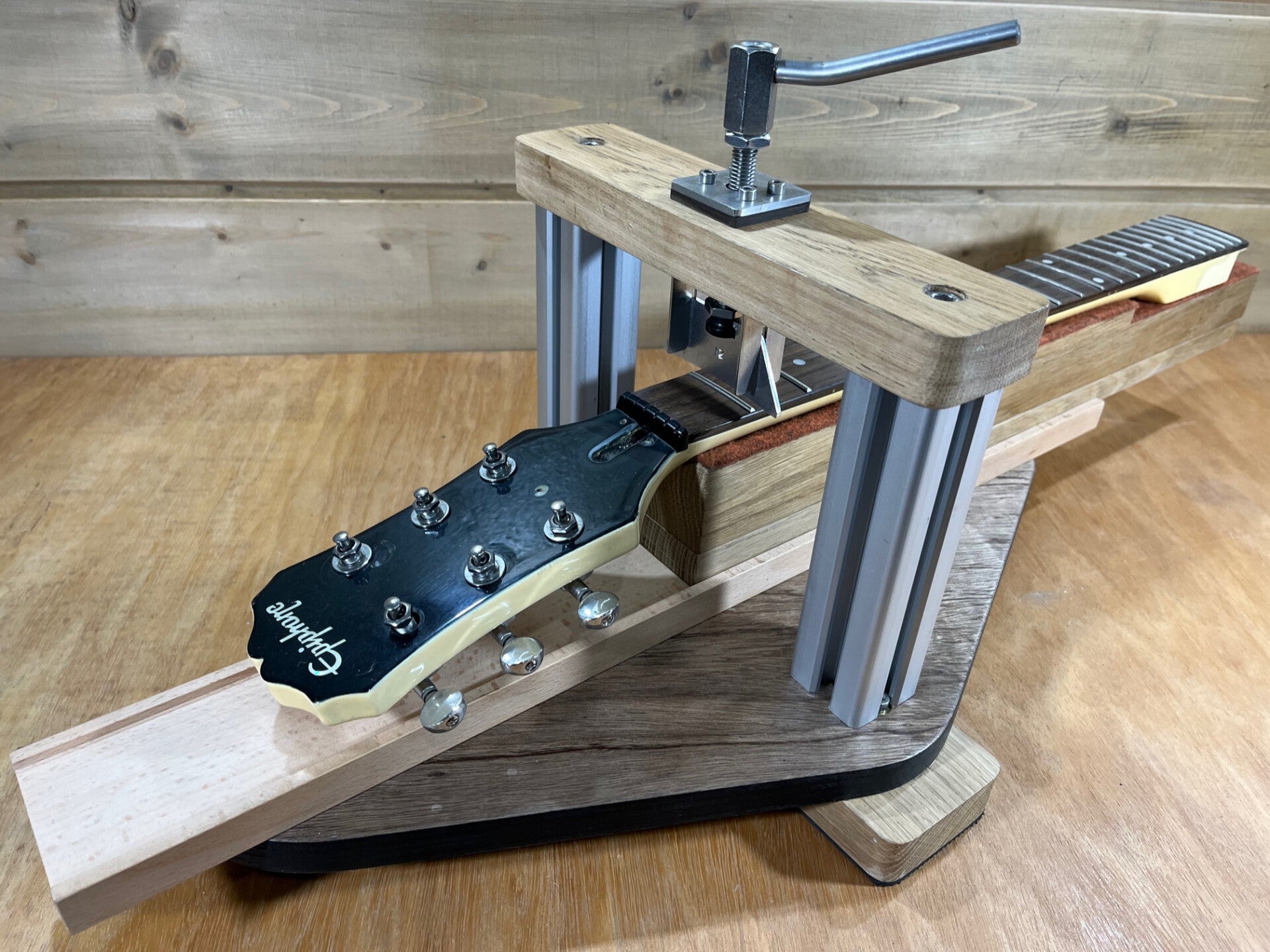 GMC Luthier Tools self-contained neck fret press shown on a workbench pressing an epiphone neck at the 1st fret.
