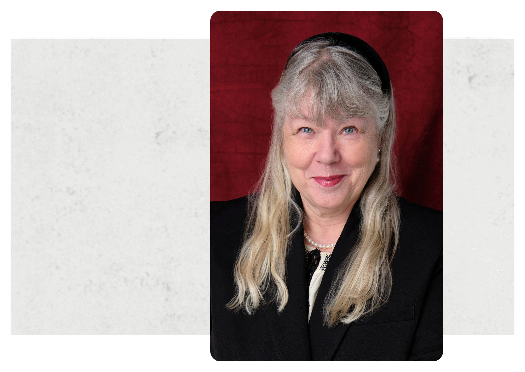Formal headshot of woman with long blonde hair and black jacket against a red backdrop