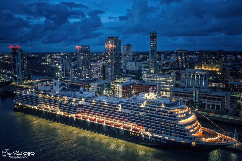 Aerial view of a Holland America Line cruise ship illuminated beside Liverpool’s waterfront at blue hour, photographed by Mike McMahon.