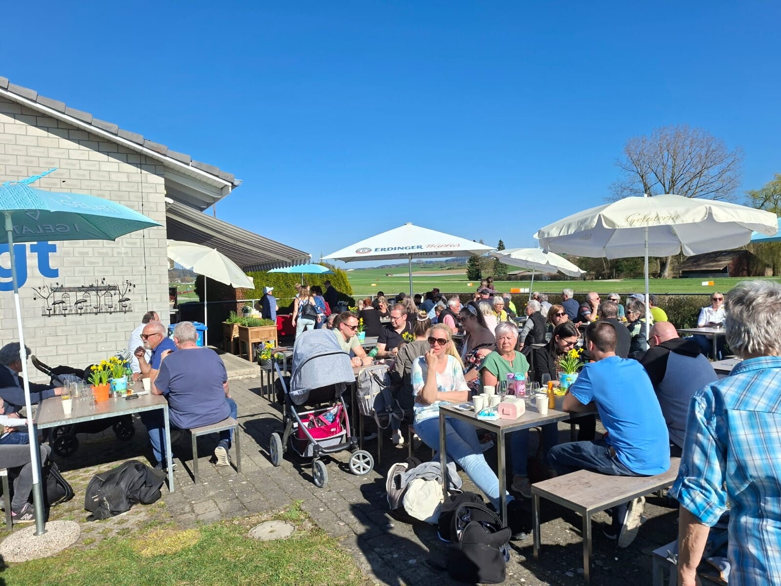 Gaste auf der Terasse des Flughafenbeizlis neben der Piste