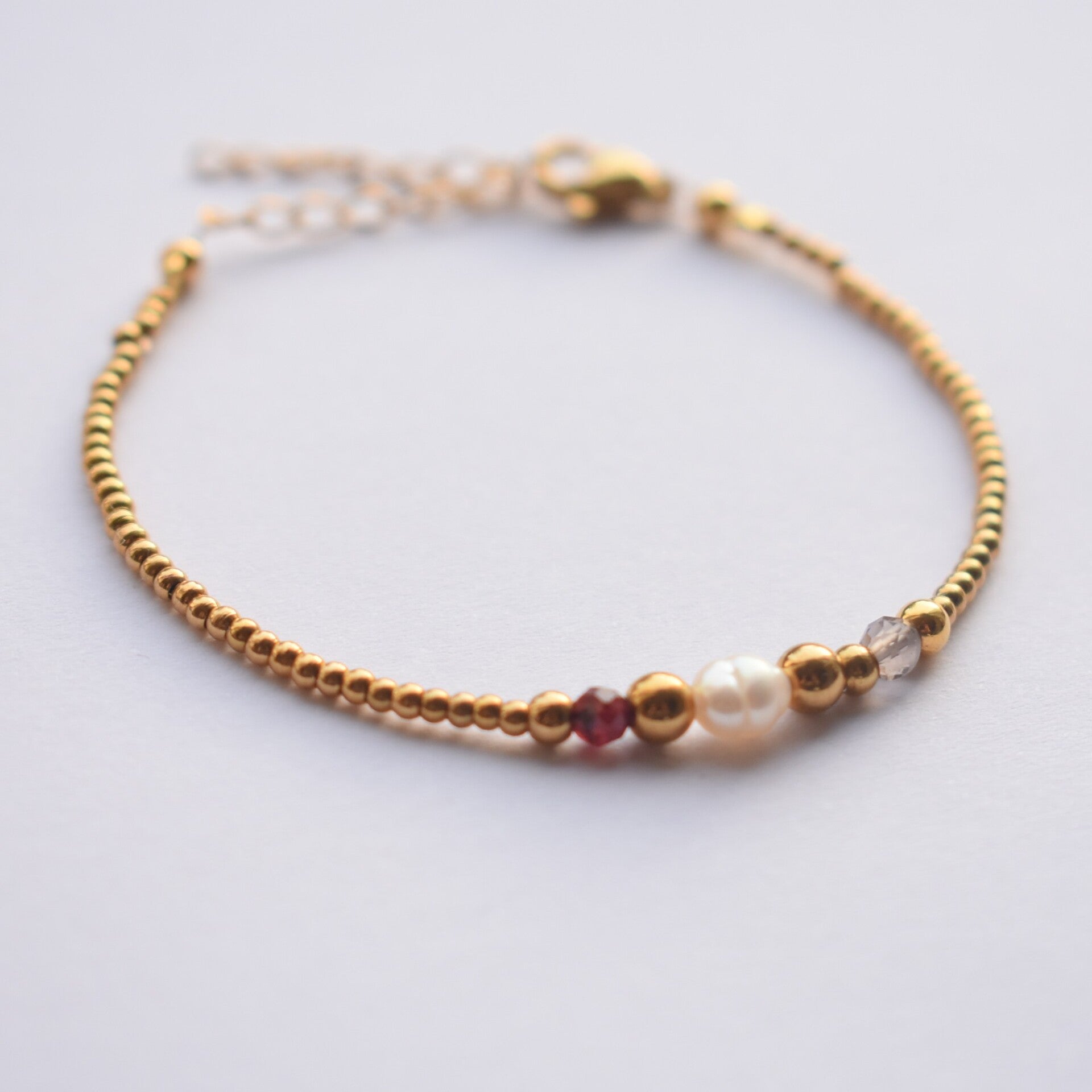 Gouden parel armband met edelstenen granaat en rookkwarts