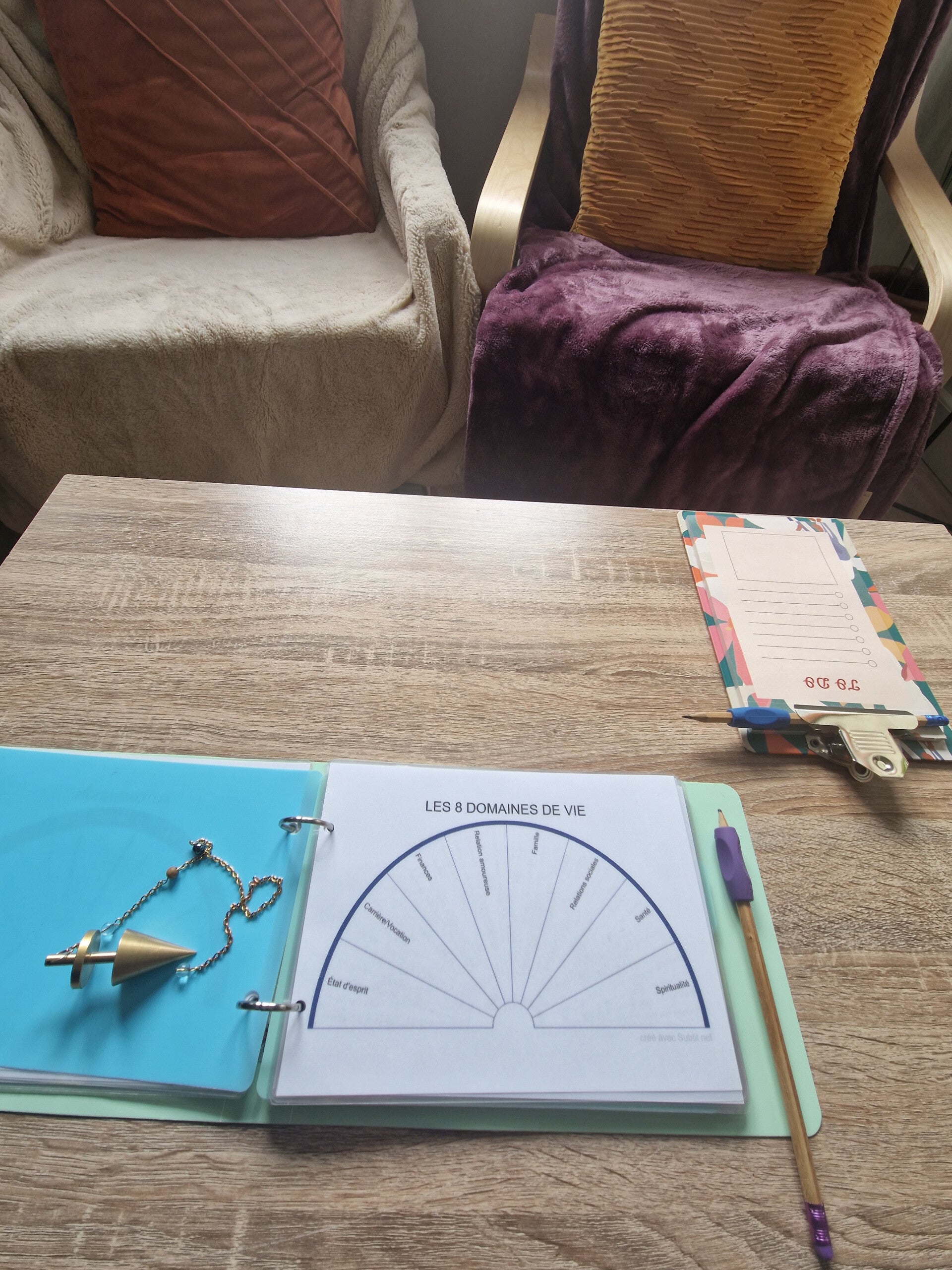 Gros plan sur un pendule de radiesthésie posé sur le cadran des 8 Domaines de Vie lors d'un coaching ou un rééquilibrage énergétique chez Isabelle FELIX Coaching.