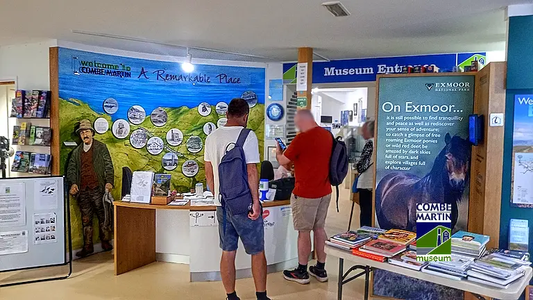 Visitors being greeted at the front desk inside Combe Martin Museum’s warm, friendly interior.