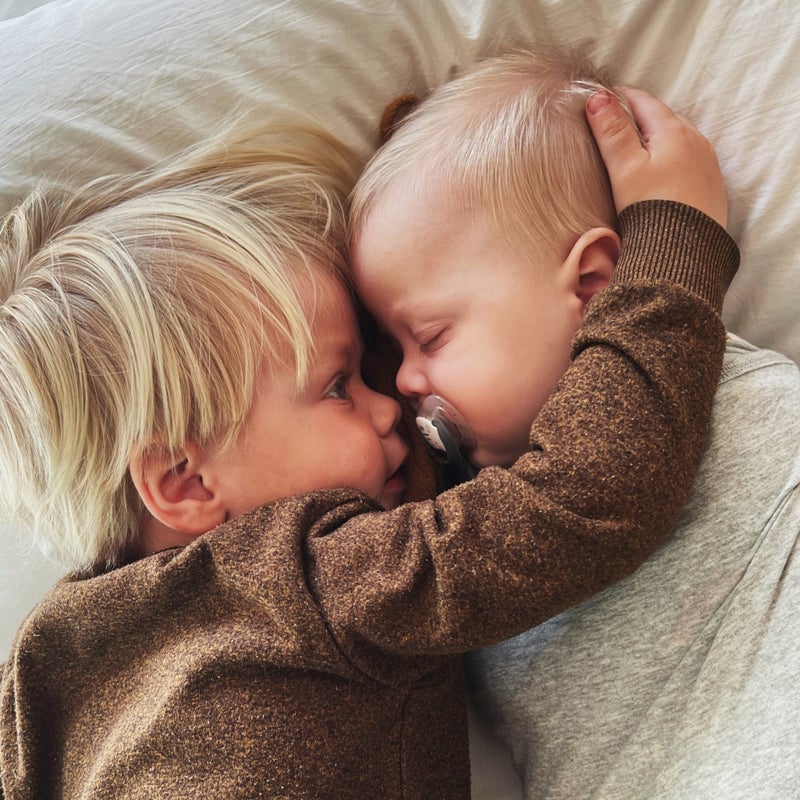 Grote broer kijkt liefdevol naar zijn babyzusje – geboortebord tuin broer of zus, liefdevolle geboorteaankondiging