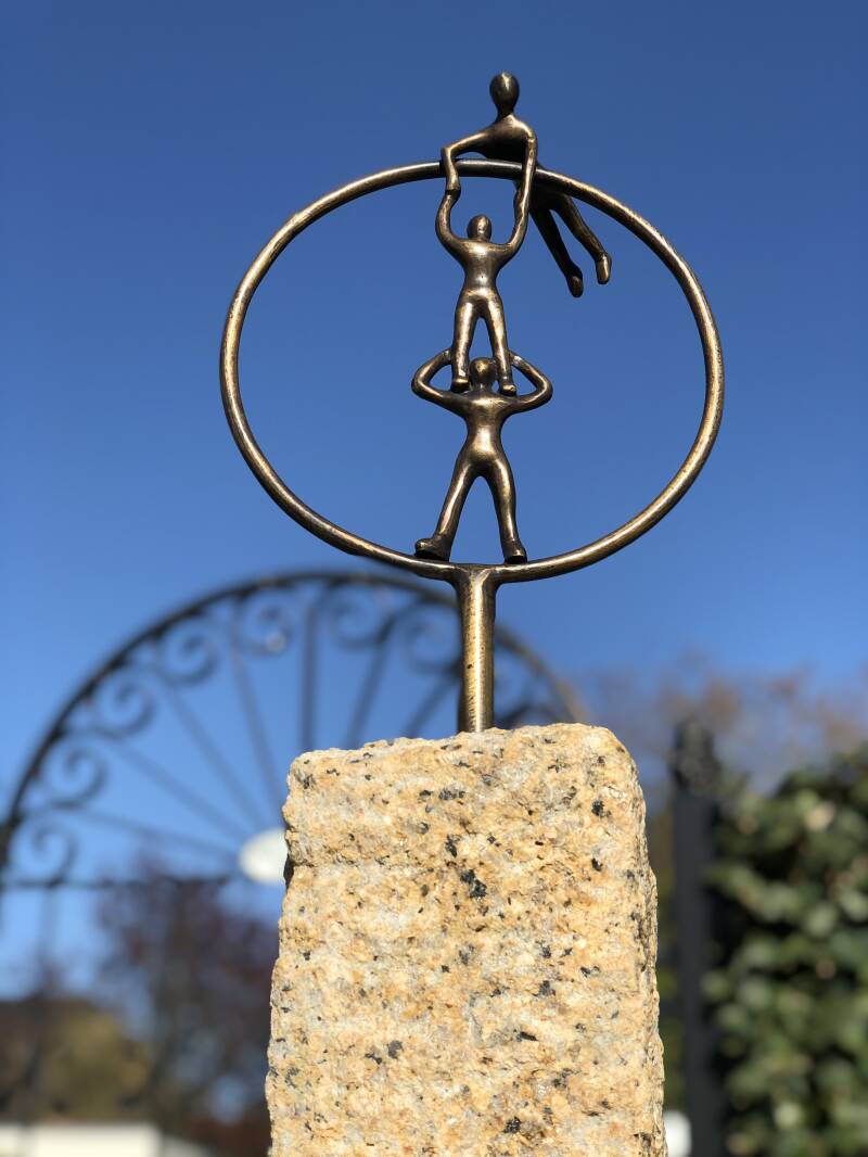 Circus act van drie personen in een cirkel in Brons op natuurstenen sokkel