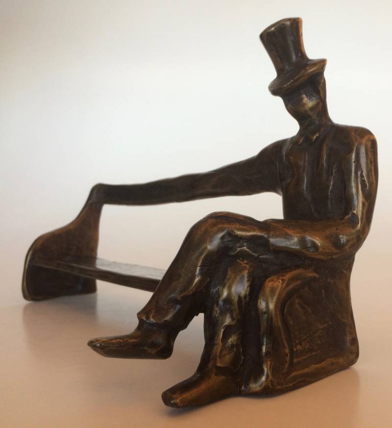 Bronzen beeld van een echte bankzitter - man zit op lange bank