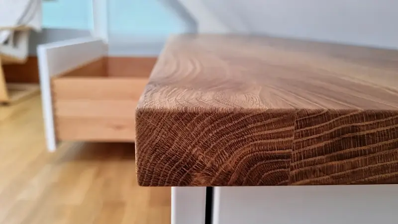 Detail einer maßgefertigten Schlafzimmer-Kommode mit weißem Korpus und massiver geölter Eichenplatte.
