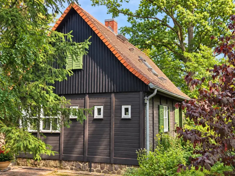 Gesamtansicht eines Ferienhauses im Garten mit neu gestalteter Holzfassade nach der Sanierung.