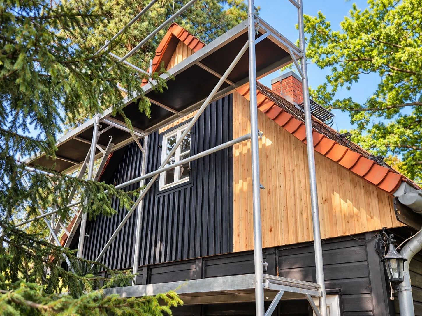 Sanierung des Giebels eines Ferienhauses mit Gerüst und neu aufgebauter Holzverkleidung.