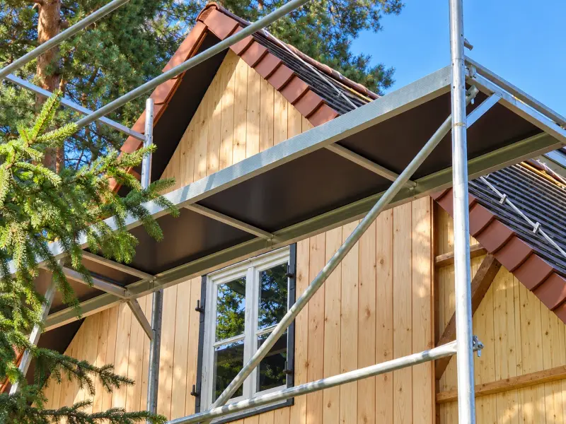 Detailaufnahme der neuen Holzfassade eines Ferienhauses mit Gerüst und frisch montierter Holzverschalung.