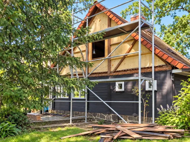 Ferienhaus mit Gerüst während der Sanierung, teilweise geöffneter Fassade und zurückgebauten Holzverkleidungen.