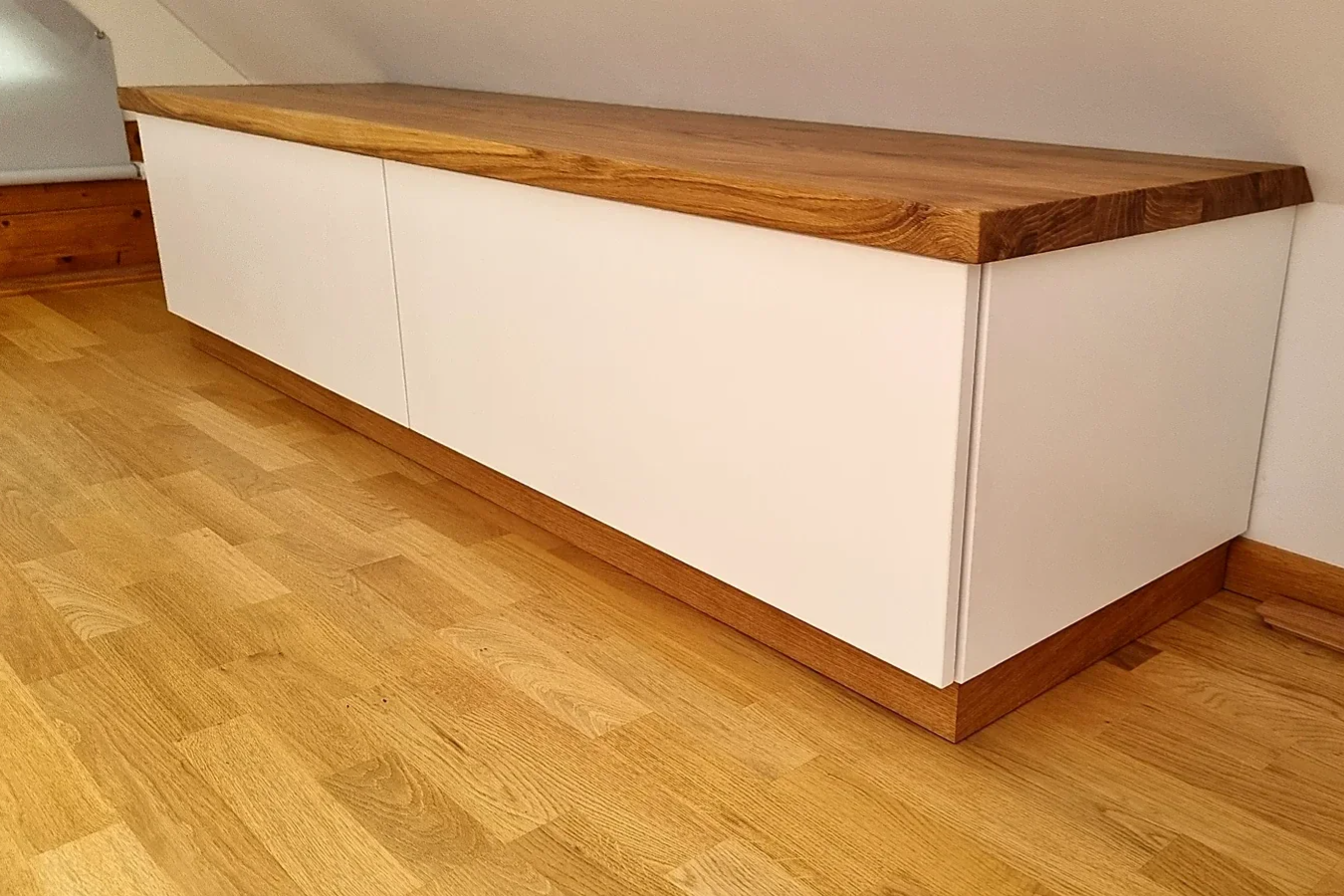 Weiße Kommode für das Schlafzimmer mit zwei Schubladen, massiver geölter Eichenplatte und an die Parkettsockelleisten angepasstem Möbelsockel
