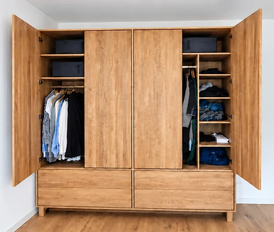 Geöffneter Kleiderschrank aus Eiche mit maßgefertigter Innenaufteilung, Kleiderstangen, Fachböden und Schubladen.