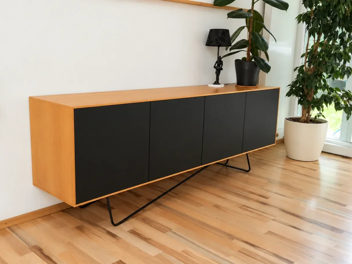 Modernes Lowboard aus Erle mit schwarzen Fronten auf filigranem schwarzem Metallgestell.