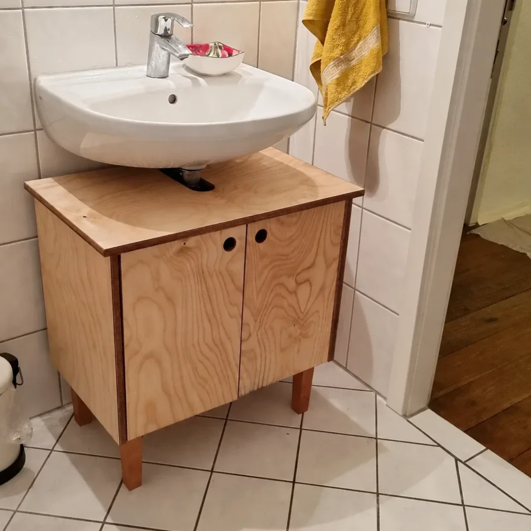 Eingebauter Waschtischunterschrank aus geöltem Pappelsperrholz unter einem weißen Waschbecken  Bildunterschrift