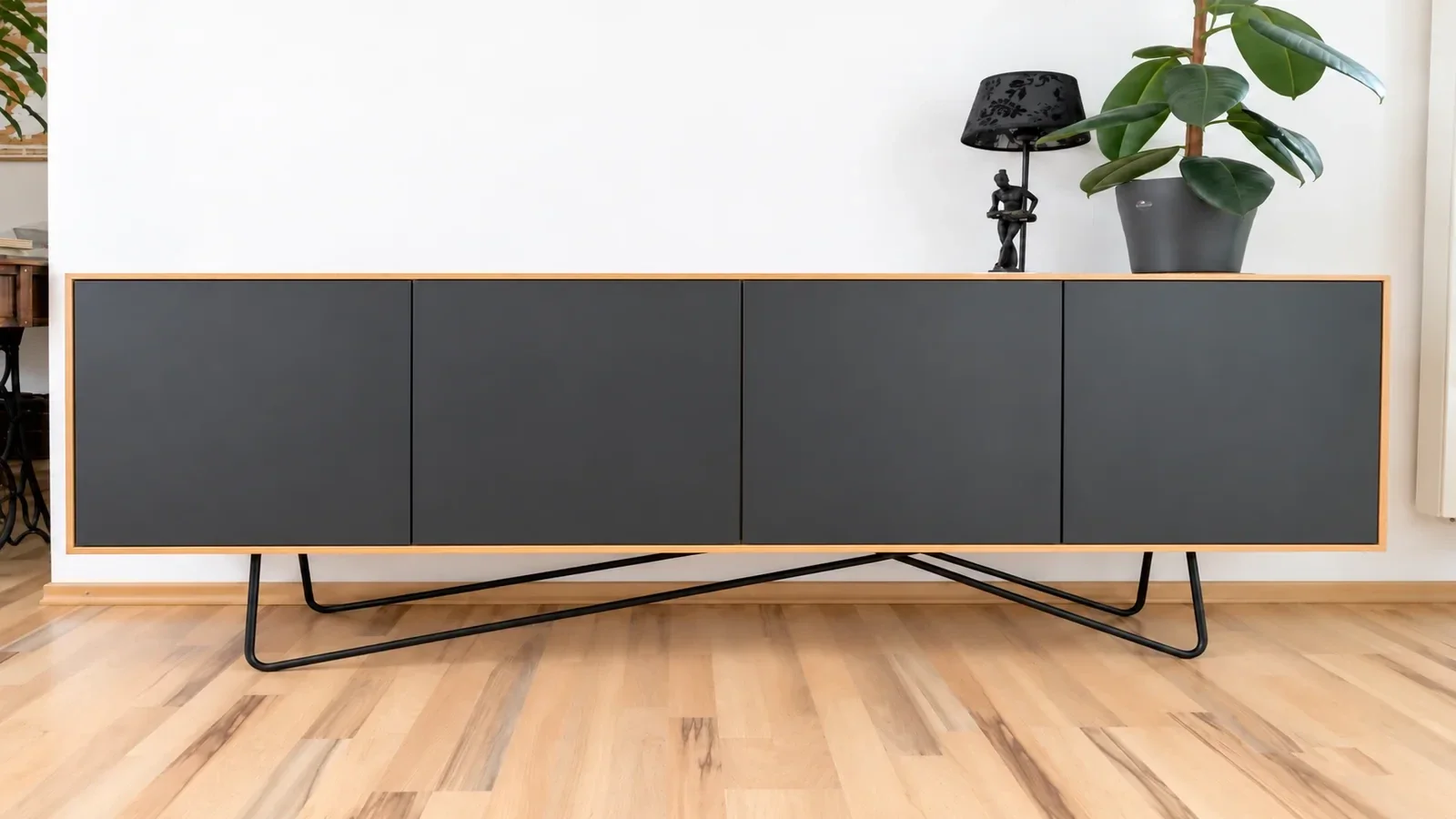 Frontalansicht eines Lowboards aus Erle mit vier schwarzen Fronten und schlankem schwarzem Metallgestell.