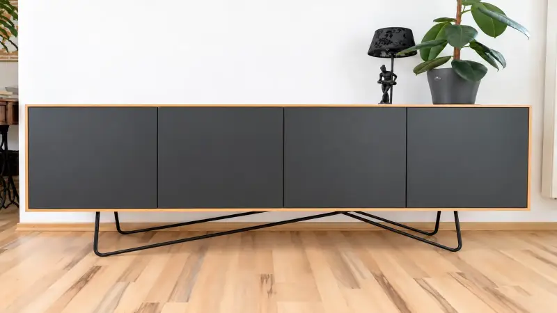 Frontalansicht eines Lowboards aus Erle mit vier schwarzen Fronten und schlankem schwarzem Metallgestell.