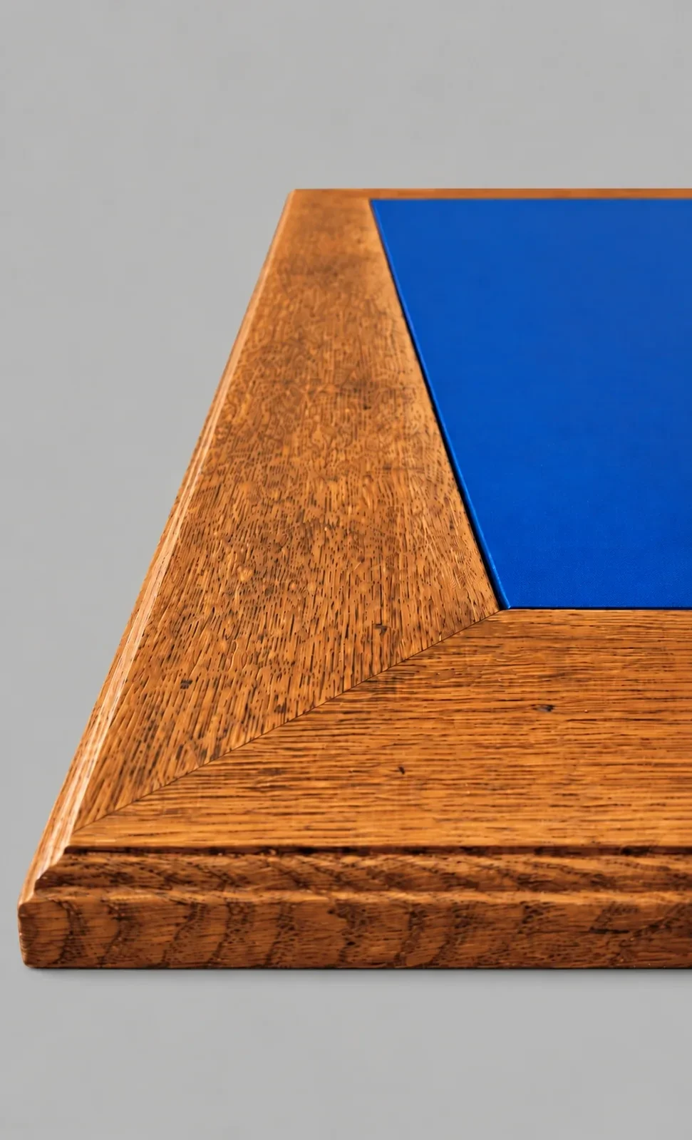Restaurierte Schreibtischplatte mit aufgearbeitetem Holzrahmen und neu eingesetzter blauer Linoleumfläche.