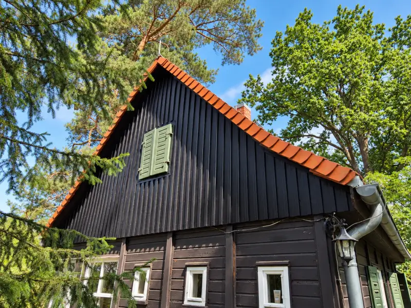 Ferienhaus mit schwarzer Holzfassade und Terrakottadach nach Abschluss der Fassadensanierung.