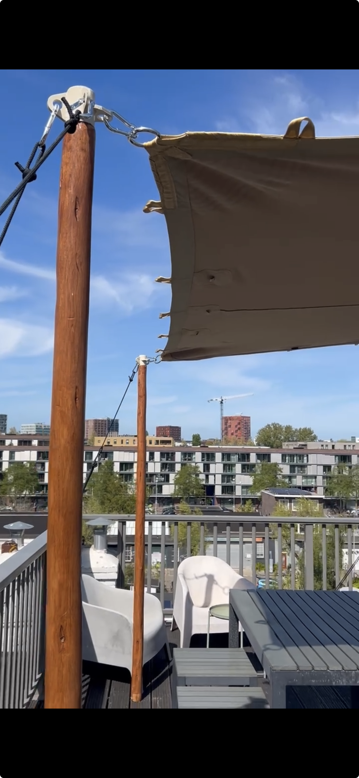 Stretchtent op maat op dakterras met houten palen en skyline uitzicht, perfect als duurzame terrasoverkapping voor horeca, events en privégebruik