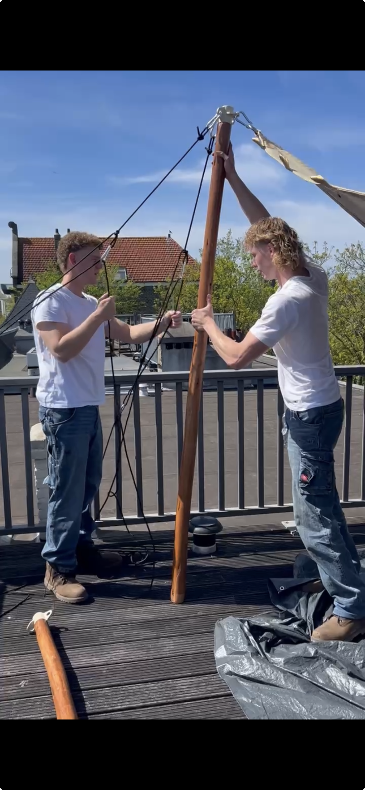 Werkwijze bij het opbouwen van een tretchtent op maat boven een dakterras met houten palen, zitgedeelte en uitzicht over de stad
