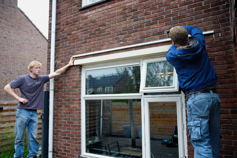 Montage van een bevestigingsrail voor een stretchtent op maat aan een bakstenen gevel