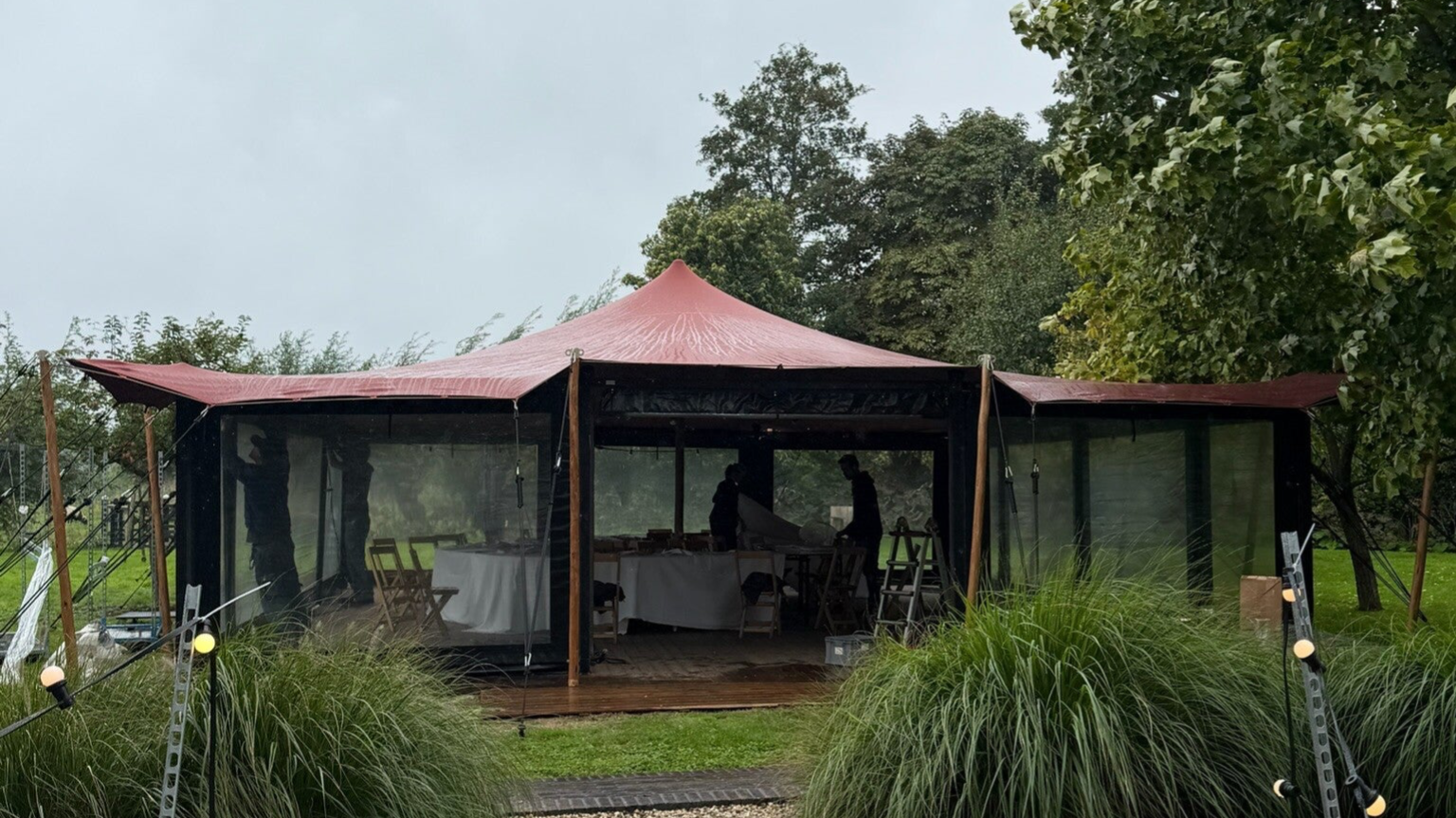 sta tafels en eettafels met banken onder stretchtent met versiering