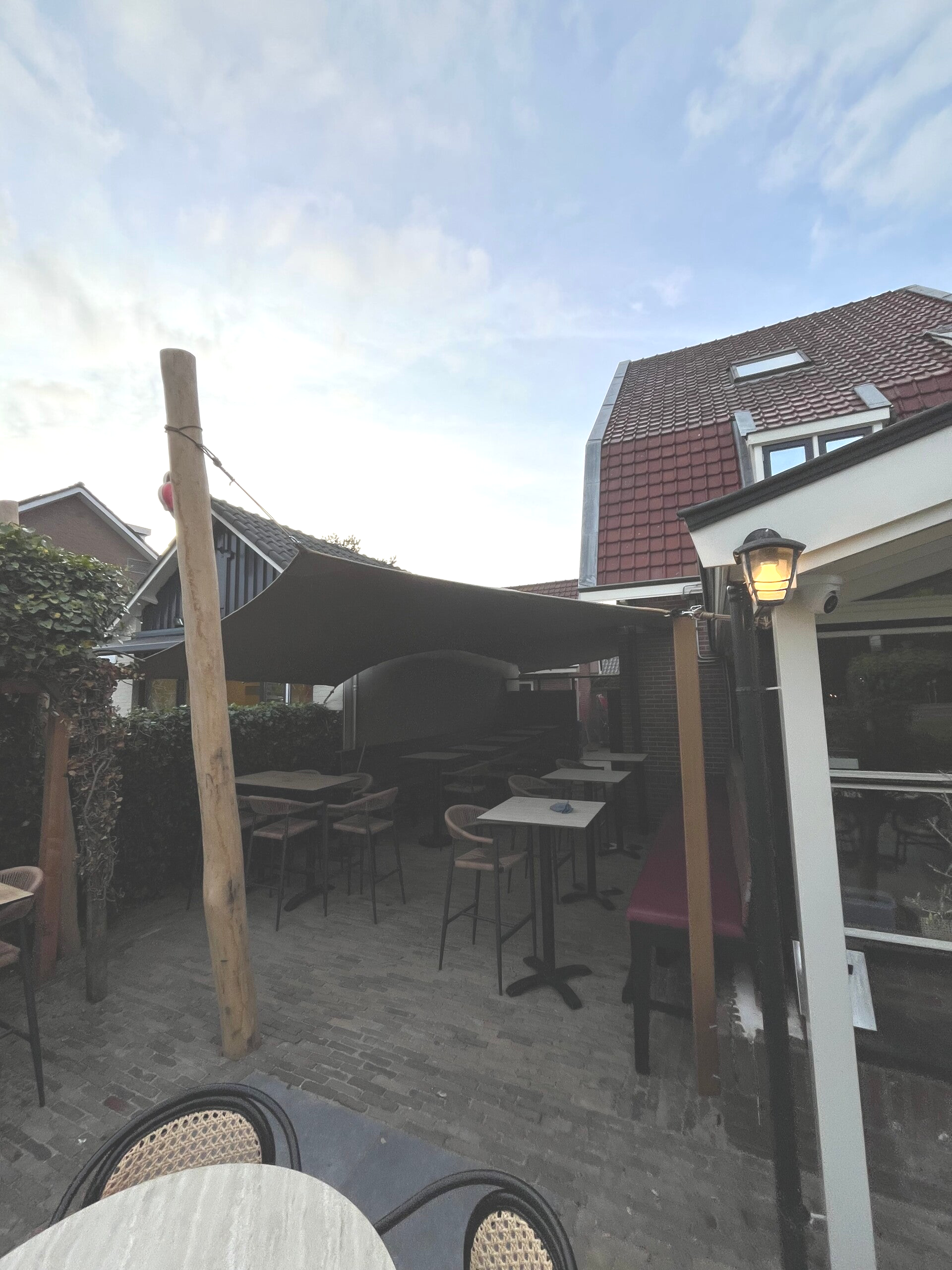 Custom fit stretchtent permanent over terras met robinia paal en stoelen en tafels onder tent