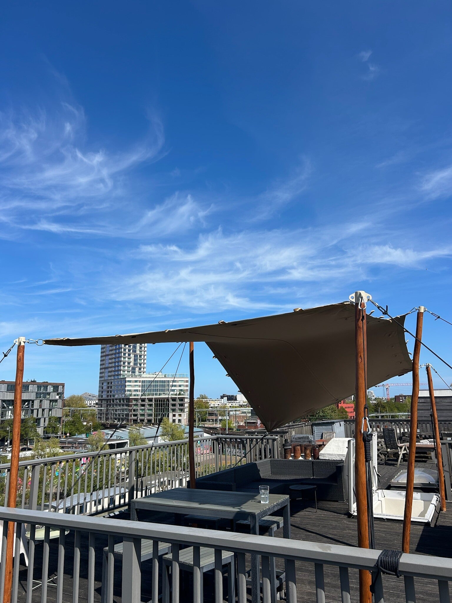 Stretchtent gehuurd en geplaatst op een stedelijk dakterras met houten palen, ideaal voor een sfeervolle loungehoek met uitzicht over de skyline