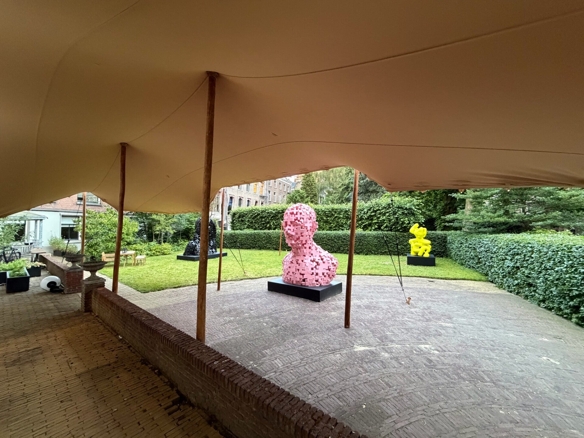 Stretchtent in grachtenpand achtertuin overdekt een zakkelijk event met kunst op de achtergrond