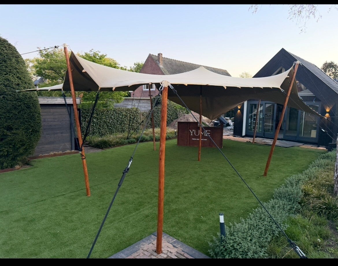 Stretchtent op maat in een ruime tuin met houten palen en luxe afwerking, perfect als sfeervolle tentoverkapping voor tuinfeest, bruiloft of evenement