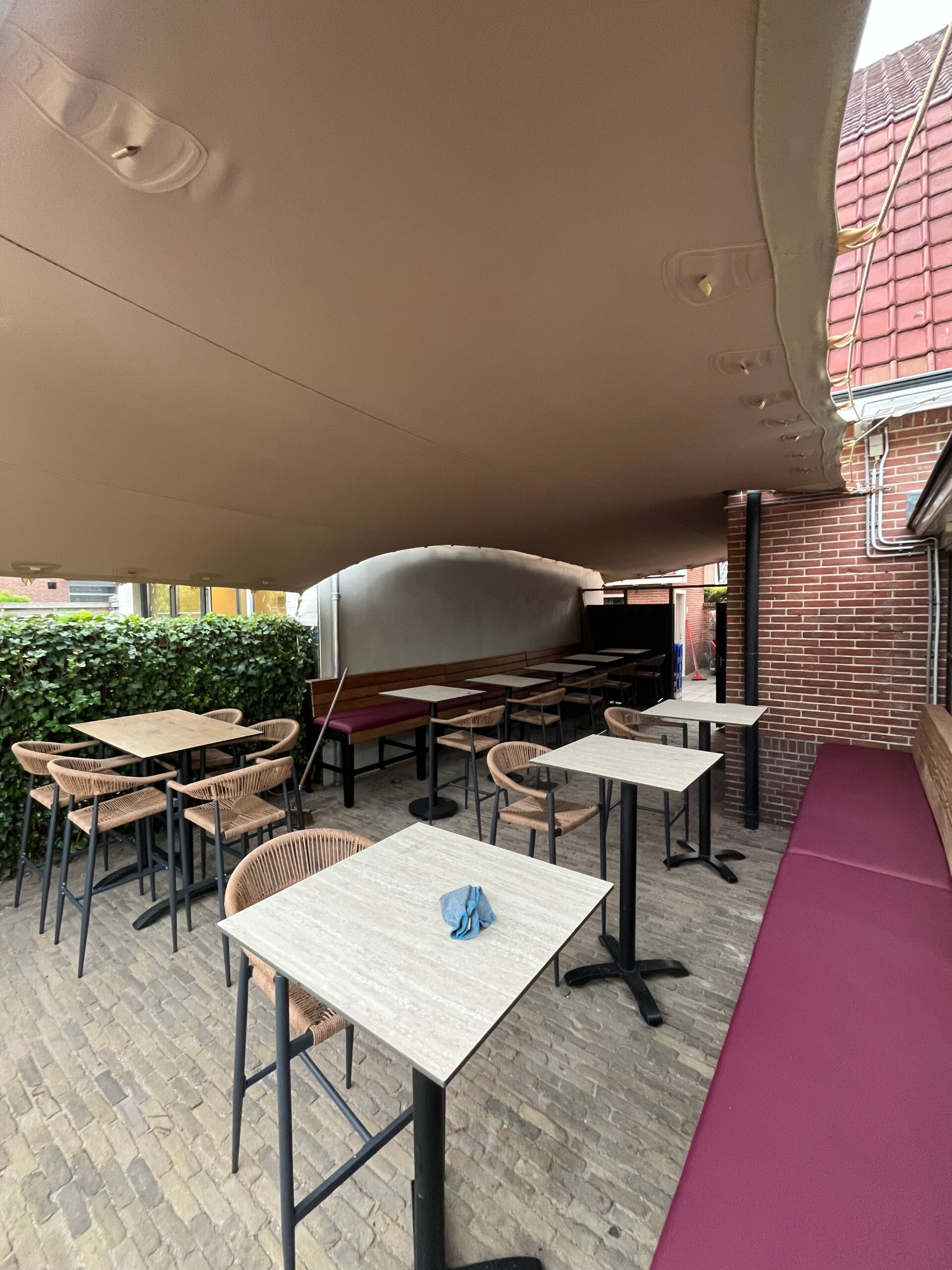 Stretchtent die tafels en stoelen overdekt op een horeca terras
