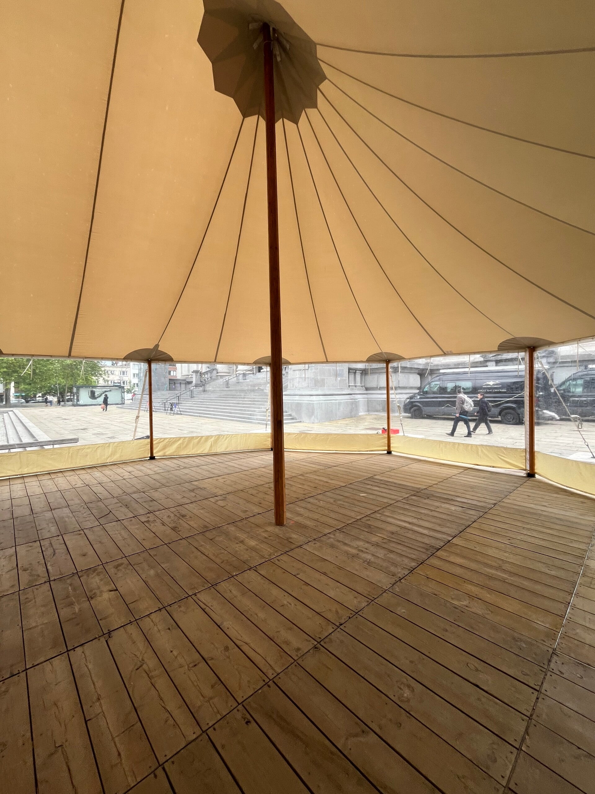 Binnenkant van de silhouettetent tijdens opbouw in Antwerpen: houten vloer, middenpaal en tentdak met spantlijnen.