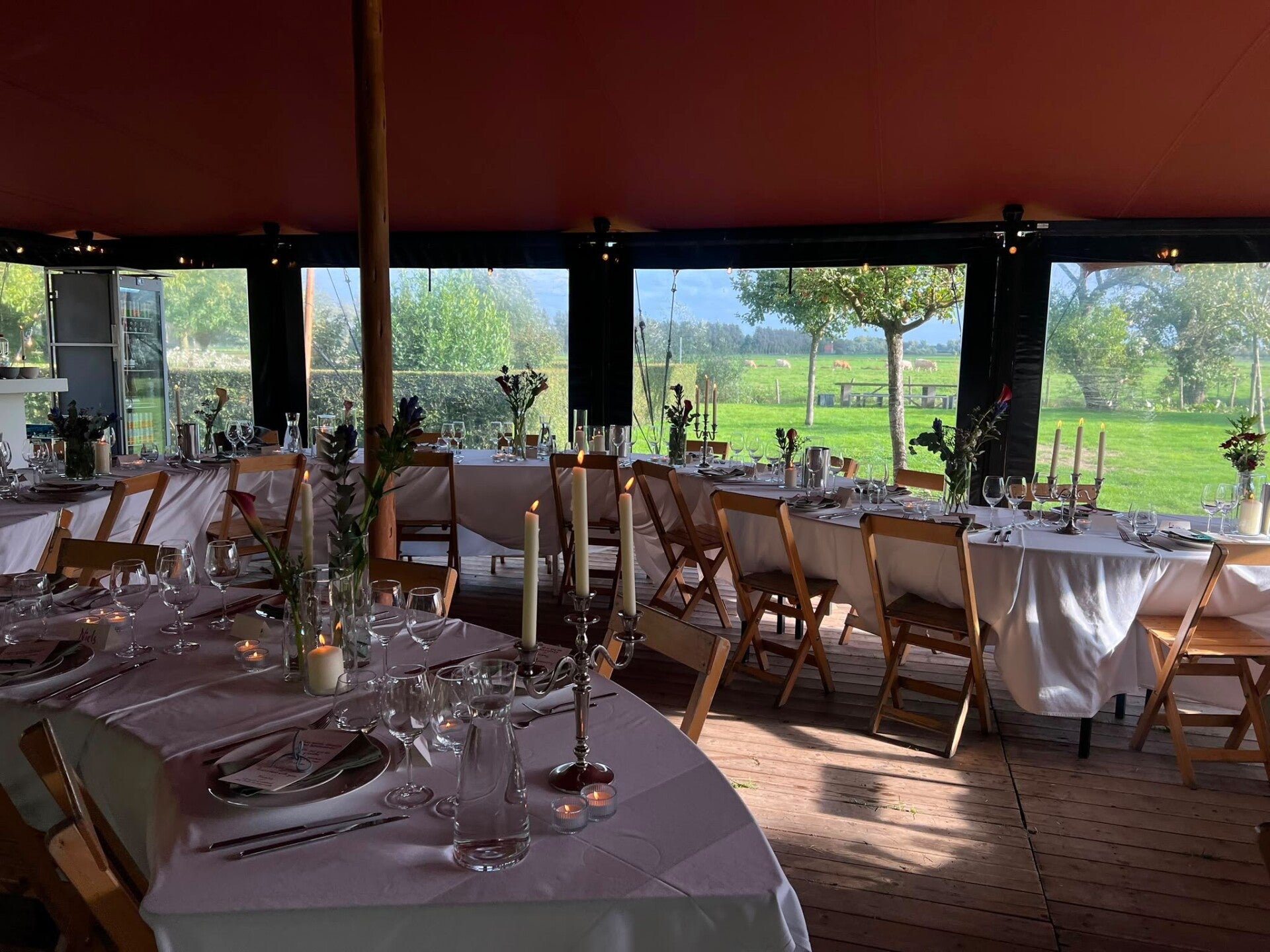 Stretchtent met zijwanden en dinertafels aangekleed in een natuurlijke omgeving
