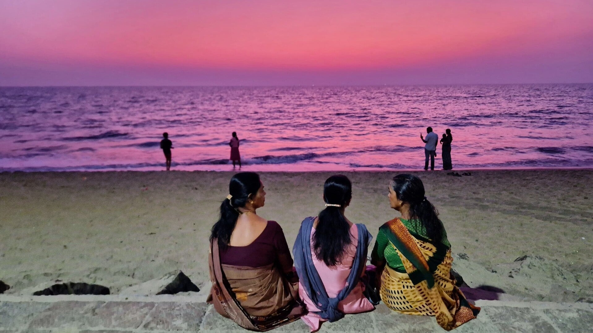 sunset beach scene with three women talking together, symbolising connection and community