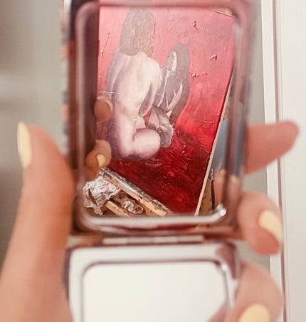 Woman looking at her paining through a mirror