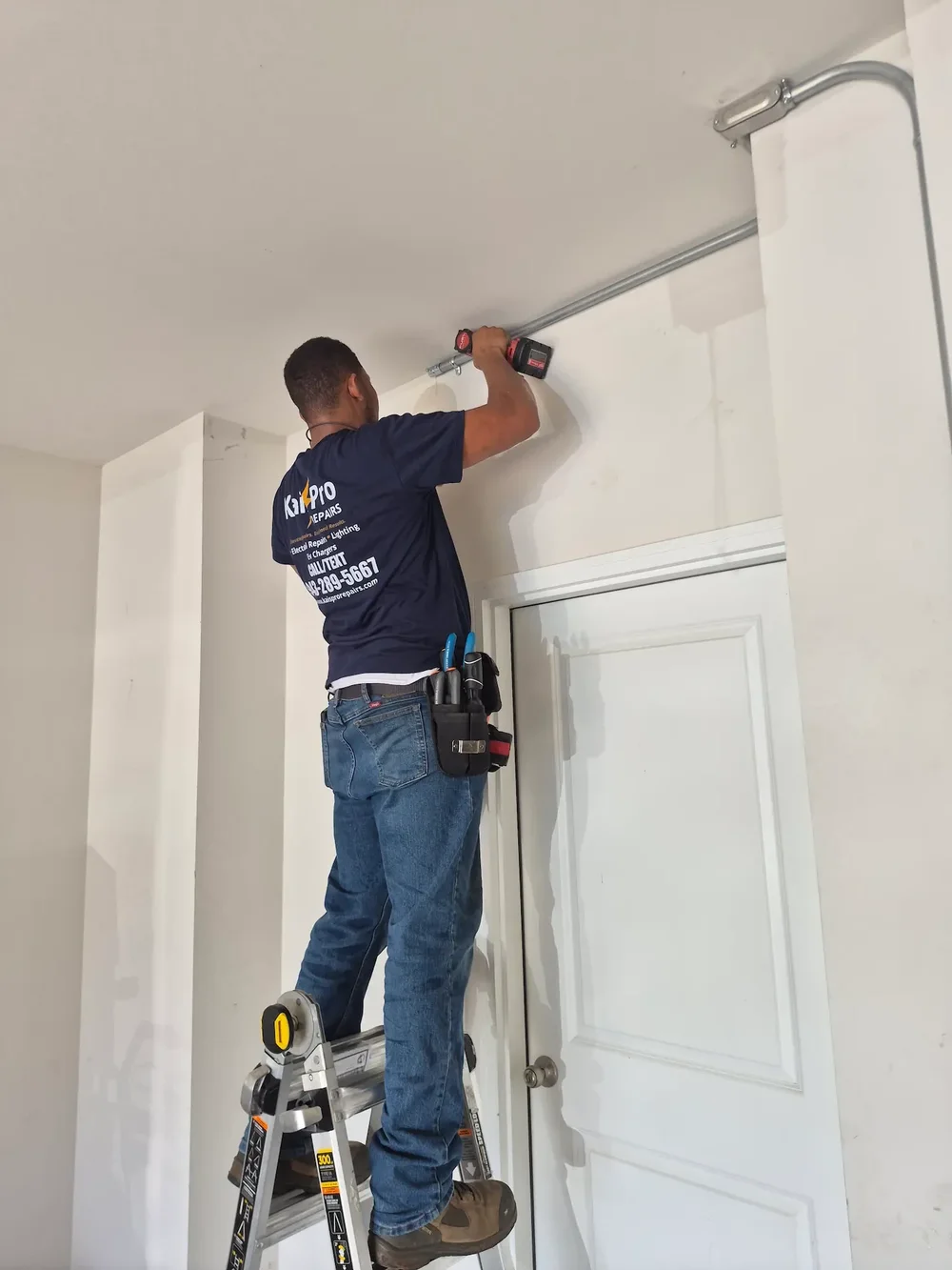 Kais Pro Repairs technician securing electrical conduit along a wall above a door