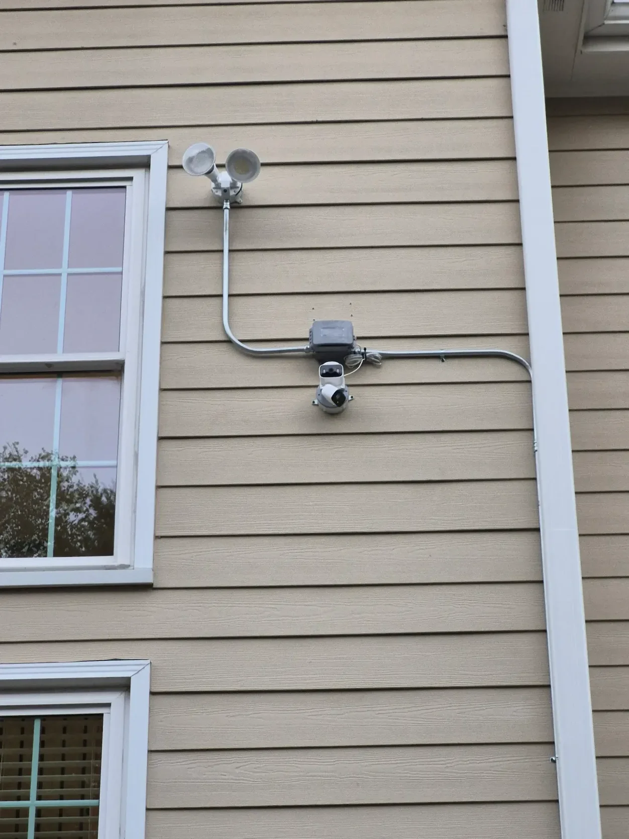 Exterior security camera and floodlight wiring installed with metal conduit at the rear of an Alpharetta Georgia home